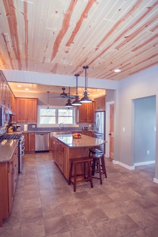 This is an example of a mid-sized country u-shaped eat-in kitchen in Boise with a farmhouse sink, raised-panel cabinets, medium wood cabinets, granite benchtops, stainless steel appliances, ceramic floors and with island.