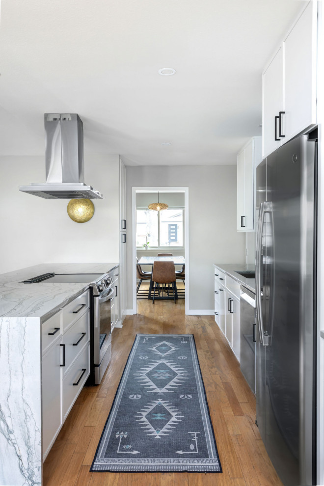 Eat-in kitchen - mid-sized transitional galley light wood floor and yellow floor eat-in kitchen idea in Austin with an undermount sink, shaker cabinets, white cabinets, quartzite countertops, stainless steel appliances, a peninsula and gray countertops