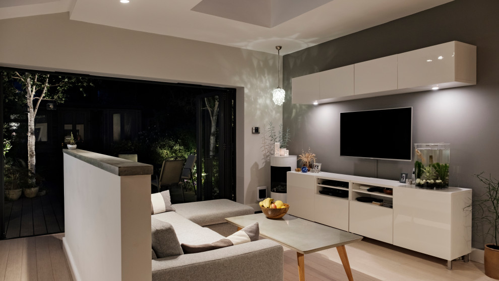 This is an example of a mid-sized contemporary open concept living room in London with grey walls, bamboo floors, a corner fireplace and white floor.