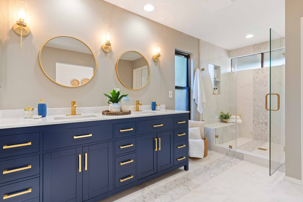 Идея дизайна: главная ванная комната среднего размера в стиле фьюжн с фасадами в стиле шейкер, синими фасадами, душем в нише, раздельным унитазом, белой плиткой, керамогранитной плиткой, серыми стенами, полом из керамогранита, врезной раковиной, столешницей из искусственного кварца, белым полом, душем с распашными дверями, белой столешницей, нишей, тумбой под две раковины и напольной тумбой