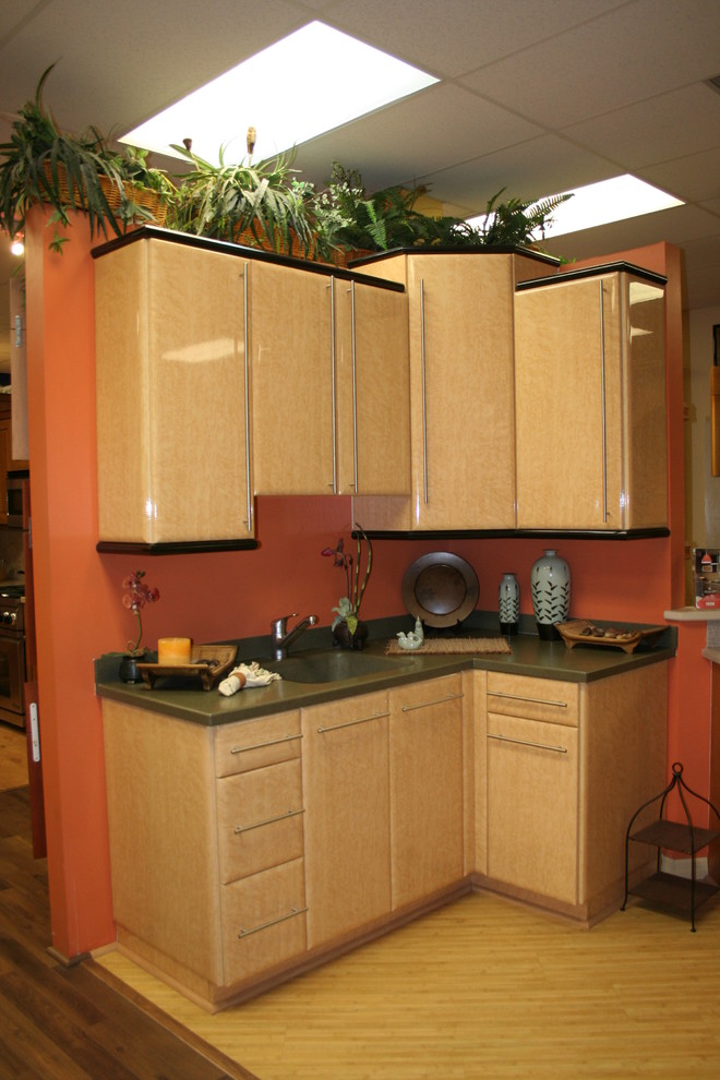 This is an example of a small asian l-shaped eat-in kitchen in Miami with an undermount sink, raised-panel cabinets, beige cabinets, solid surface benchtops, orange splashback, stainless steel appliances, laminate floors and no island.