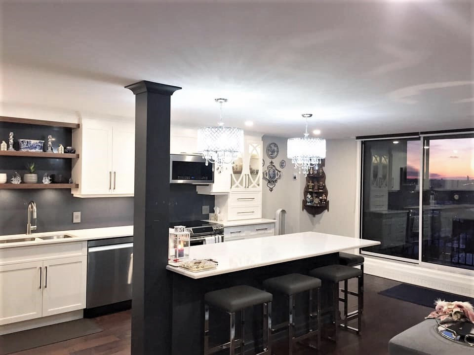 This is an example of a mid-sized transitional l-shaped eat-in kitchen in Ottawa with an undermount sink, recessed-panel cabinets, white cabinets, quartz benchtops, blue splashback, engineered quartz splashback, stainless steel appliances, dark hardwood floors, with island, brown floor and white benchtop.