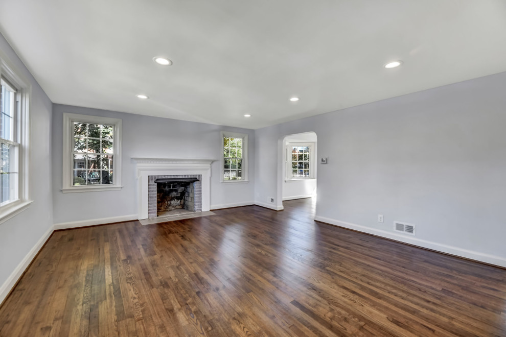 Photo of a large traditional open concept living room in Baltimore with grey walls, medium hardwood floors, a wood stove, a brick fireplace surround, no tv and brown floor.