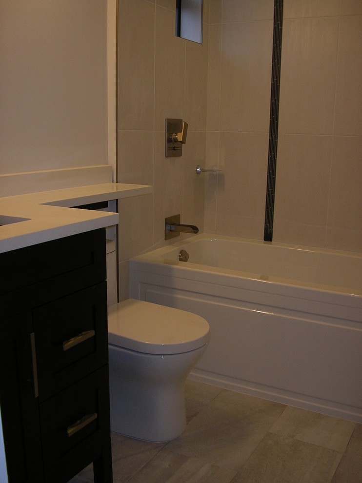 This is an example of a contemporary bathroom in Vancouver with an undermount sink, furniture-like cabinets, brown cabinets, quartzite benchtops, an alcove tub, a shower/bathtub combo, a one-piece toilet, beige tile and porcelain tile.