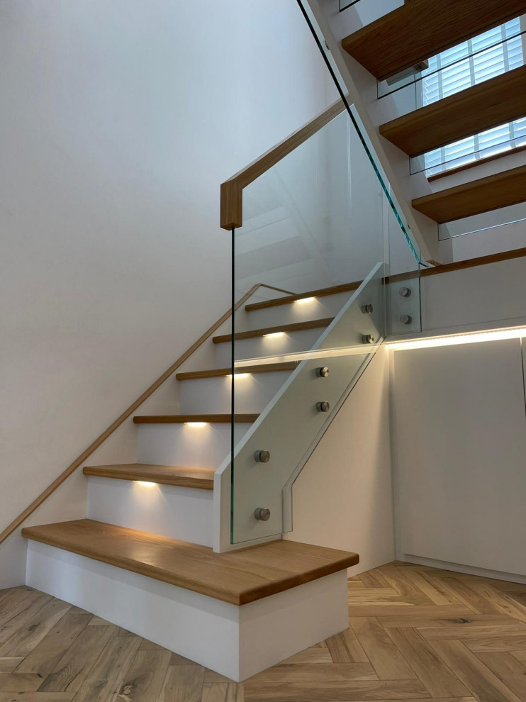 Mid-sized modern wood u-shaped staircase in Cheshire with open risers and glass railing.