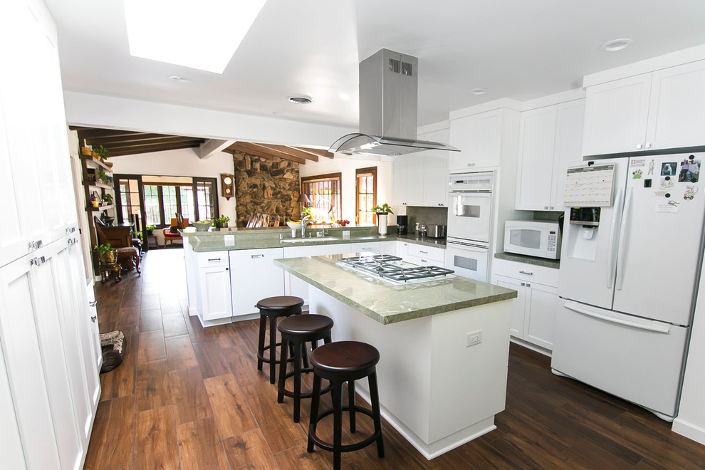 Design ideas for a large modern l-shaped eat-in kitchen in Los Angeles with a double-bowl sink, raised-panel cabinets, white cabinets, quartz benchtops, green splashback, stone slab splashback, white appliances, dark hardwood floors and with island.