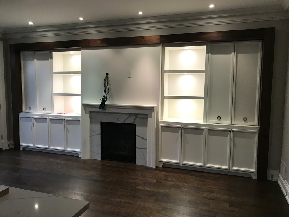 Example of a mid-sized transitional open concept and l-shaped dark wood floor and brown floor open concept kitchen design in Toronto with gray walls, a standard fireplace, a stone fireplace, an undermount sink, recessed-panel cabinets, white cabinets, solid surface countertops, gray backsplash, stone slab backsplash, paneled appliances, an island and multicolored countertops