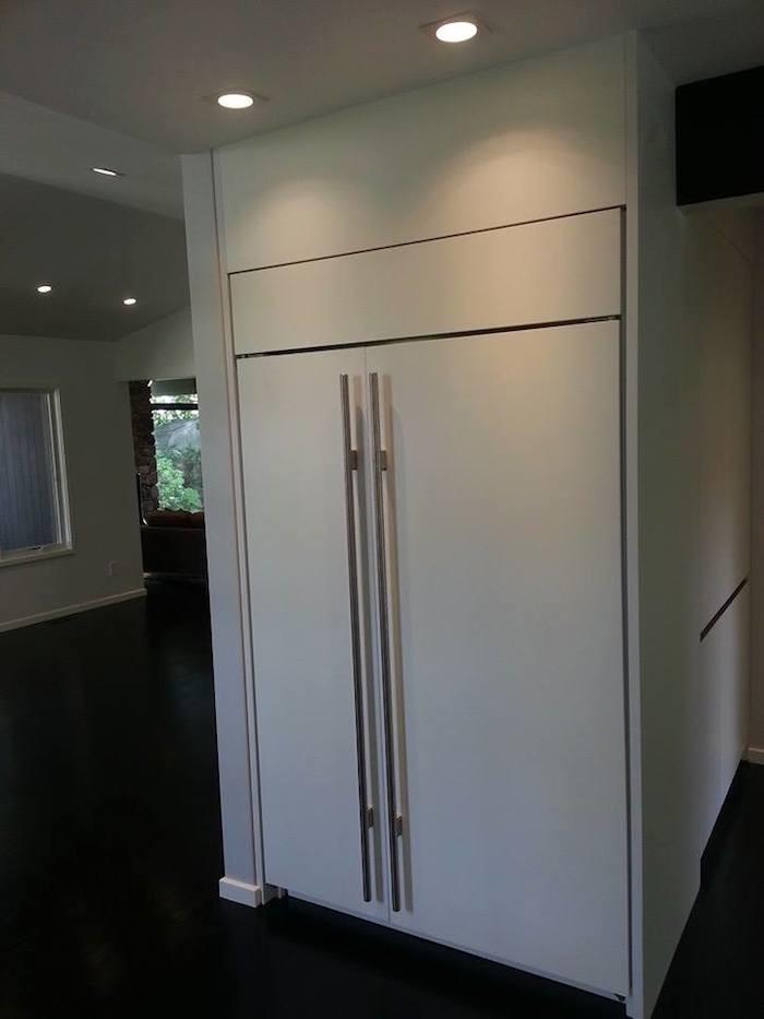 Open concept kitchen - mid-sized transitional single-wall medium tone wood floor open concept kitchen idea in Boston with a drop-in sink, flat-panel cabinets, white cabinets, granite countertops, white backsplash, stone tile backsplash, stainless steel appliances and an island