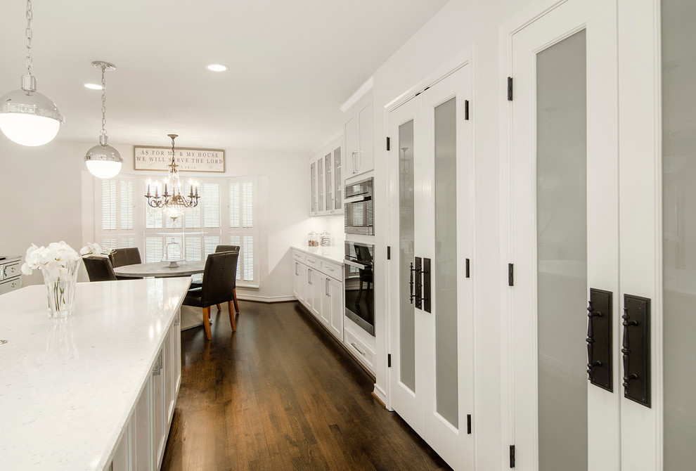 Example of a mid-sized transitional u-shaped medium tone wood floor kitchen pantry design in Dallas with a farmhouse sink, open cabinets, white cabinets, solid surface countertops, white backsplash, subway tile backsplash, stainless steel appliances and an island