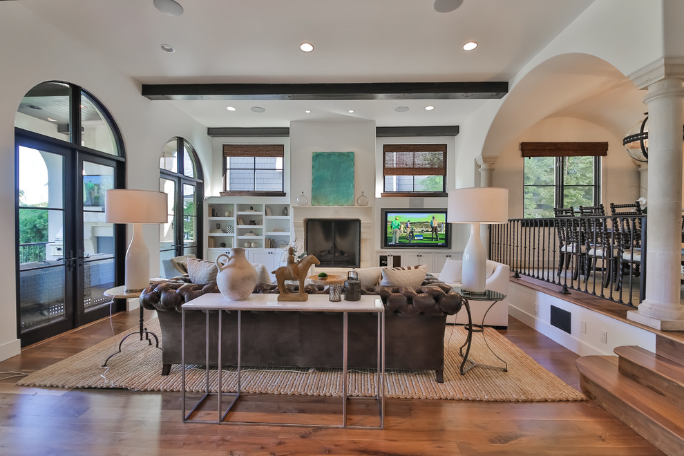 Photo of a traditional open concept living room in Los Angeles with white walls, medium hardwood floors, a standard fireplace and a wall-mounted tv.