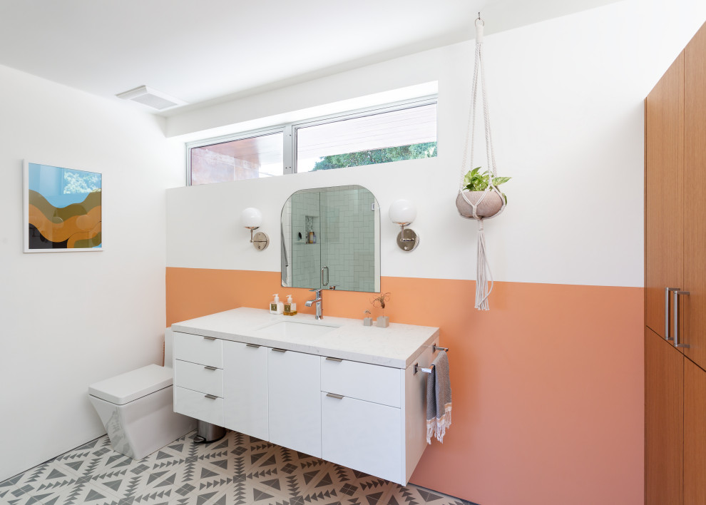 Photo of a contemporary bathroom in San Francisco with flat-panel cabinets, white cabinets, orange walls, an undermount sink, multi-coloured floor and white benchtops.