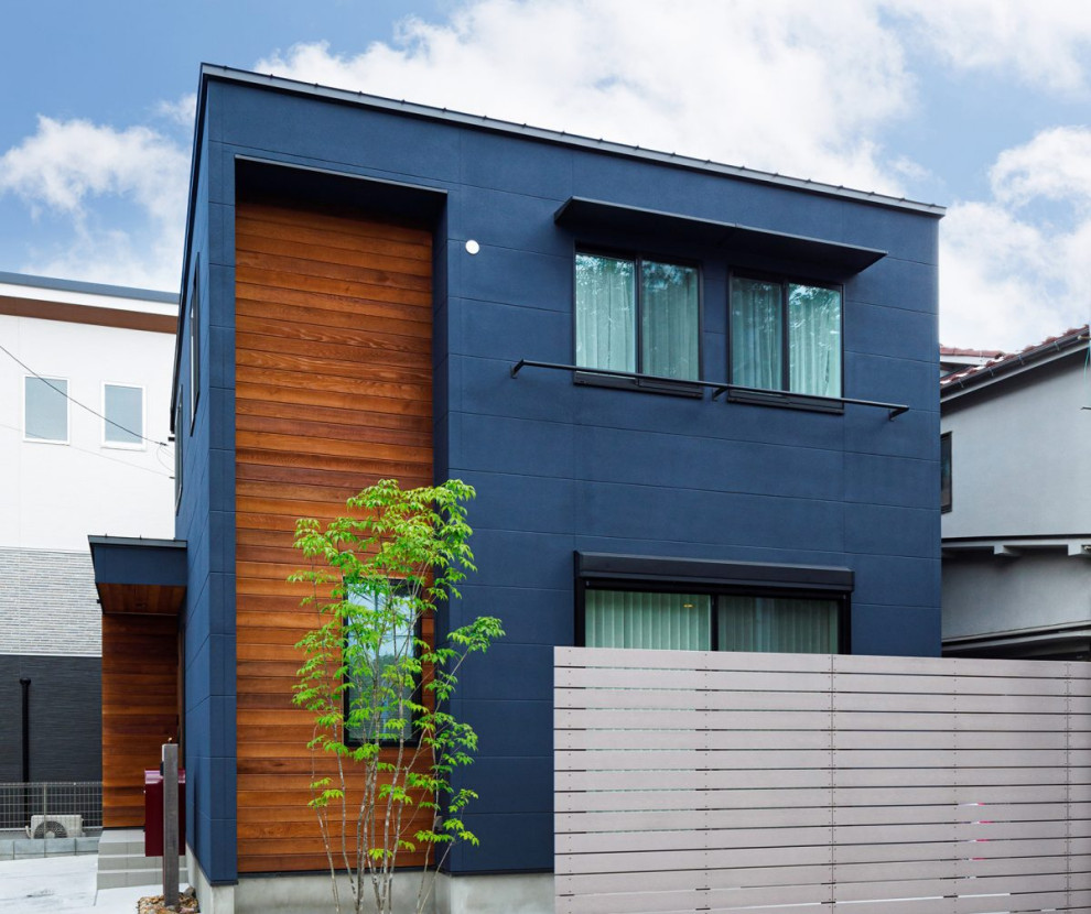 Industriell inredning av ett mellanstort blått hus, med två våningar, blandad fasad, platt tak och tak i metall