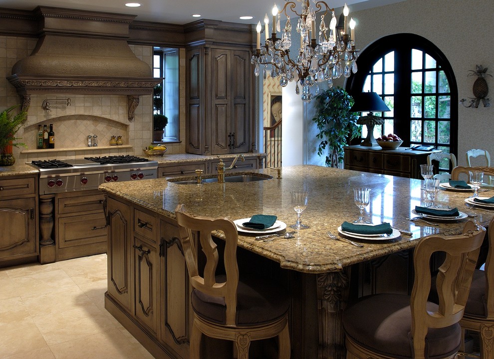 This is an example of an expansive traditional u-shaped separate kitchen in Philadelphia with a double-bowl sink, raised-panel cabinets, dark wood cabinets, glass benchtops, beige splashback, stone tile splashback, panelled appliances, travertine floors, with island and beige floor.