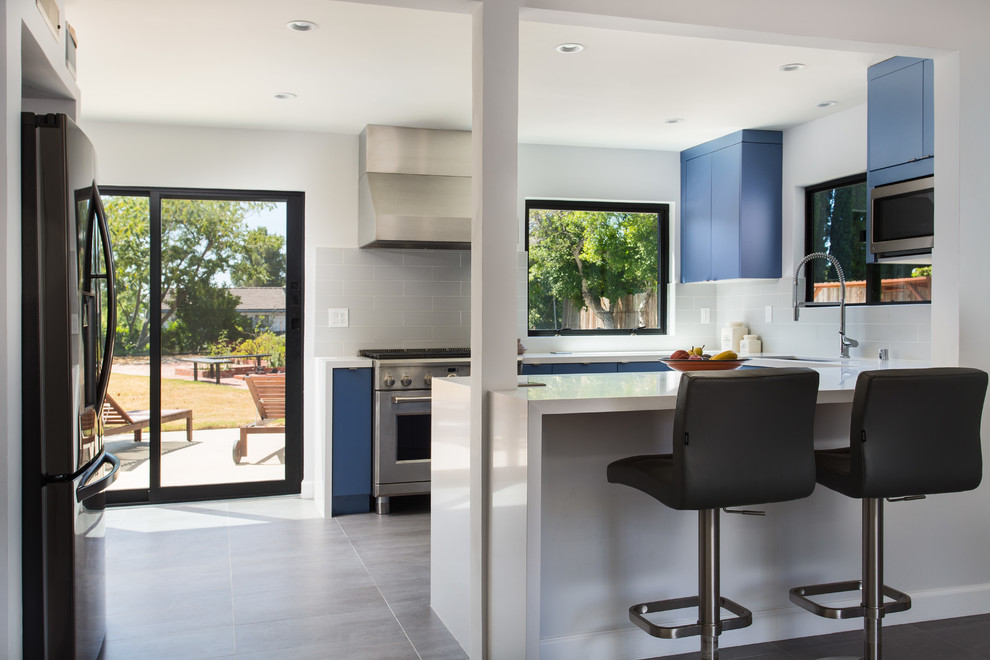 Small minimalist u-shaped porcelain tile and gray floor eat-in kitchen photo in Los Angeles with an undermount sink, flat-panel cabinets, blue cabinets, quartz countertops, gray backsplash, subway tile backsplash, stainless steel appliances, no island and white countertops