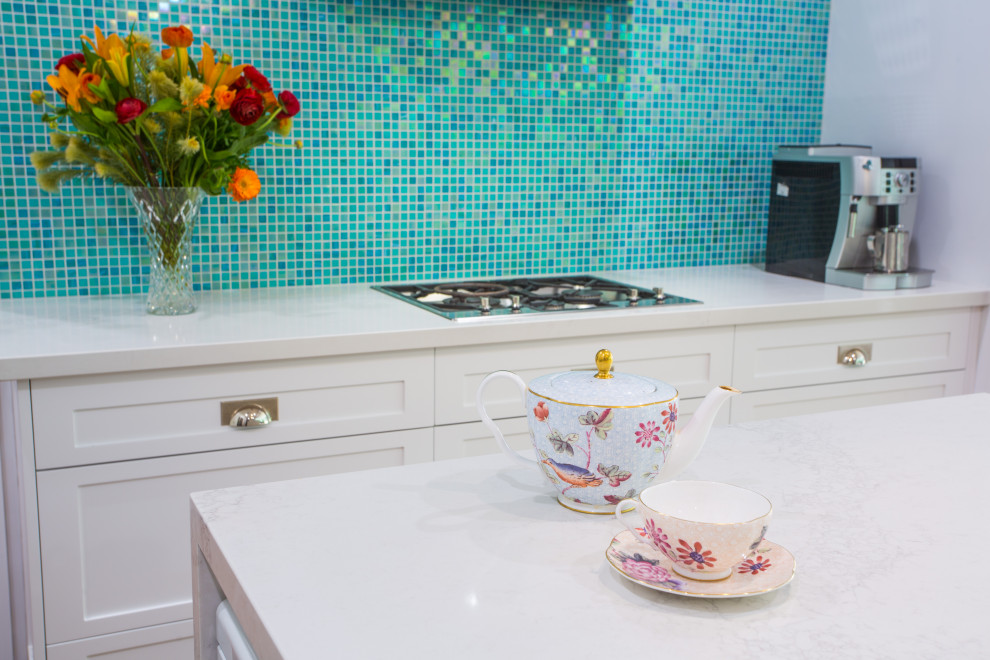 Exempel på ett mellanstort modernt vit vitt kök, med en dubbel diskho, skåp i shakerstil, vita skåp, bänkskiva i kvarts, blått stänkskydd, stänkskydd i mosaik, rostfria vitvaror, mellanmörkt trägolv och en köksö