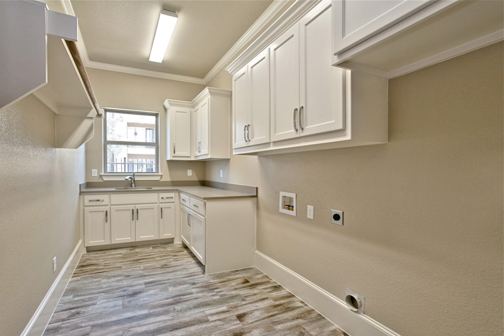 Design ideas for a large transitional l-shaped dedicated laundry room in Dallas with an undermount sink, shaker cabinets, white cabinets, granite benchtops, beige walls, painted wood floors and a side-by-side washer and dryer.