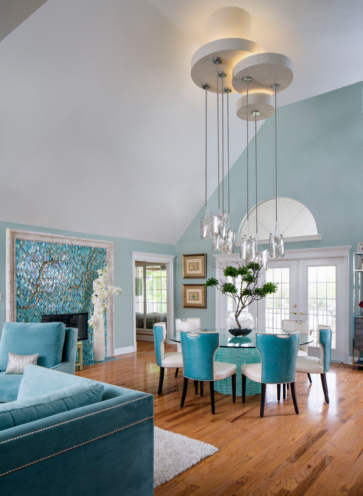Inspiration for a transitional dining room in New Orleans with blue walls, medium hardwood floors, a standard fireplace, a tile fireplace surround and brown floor.