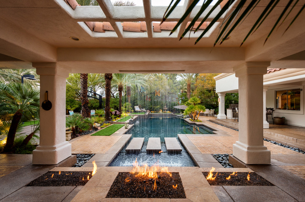Inspiration for a large transitional backyard rectangular lap pool in Las Vegas with a water feature and decking.