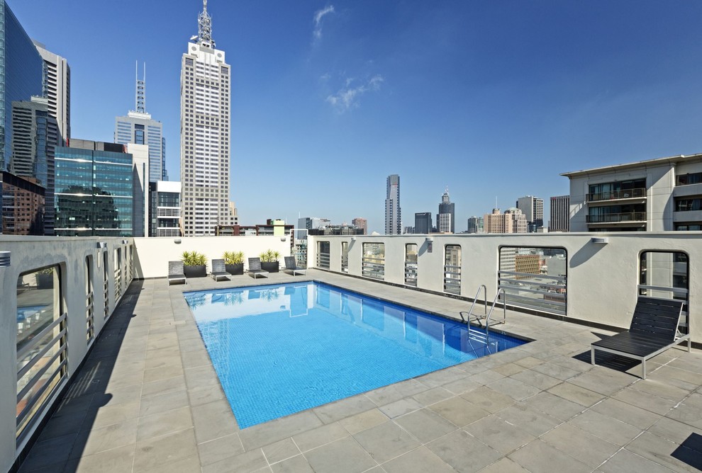 This is an example of a large contemporary rooftop rectangular pool in Melbourne with concrete pavers.