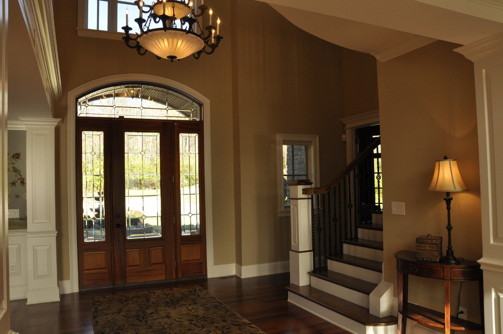 Example of a huge transitional dark wood floor and brown floor foyer design in Cincinnati with yellow walls and a dark wood front door