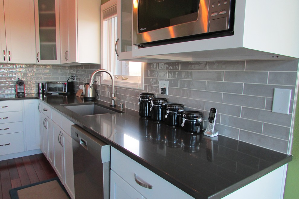 Inspiration for a mid-sized transitional l-shaped medium tone wood floor and brown floor eat-in kitchen remodel with a double-bowl sink, recessed-panel cabinets, white cabinets, gray backsplash, stainless steel appliances, an island and subway tile backsplash