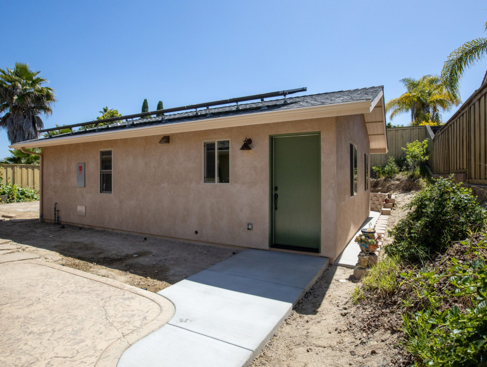 This is an example of a small and beige contemporary bungalow render house exterior in San Diego with a pitched roof and a shingle roof.