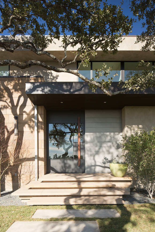 This is an example of a mid-sized contemporary front door in Austin with beige walls, limestone floors, a pivot front door and a glass front door.