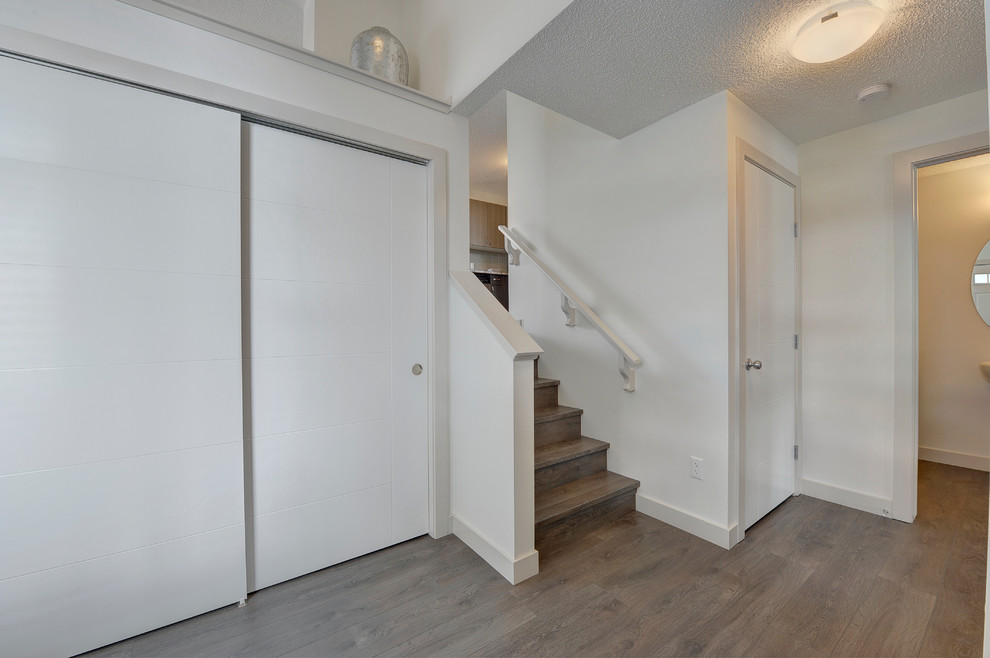 Inspiration for a mid-sized transitional laminate floor and gray floor foyer remodel in Edmonton with white walls and a white front door