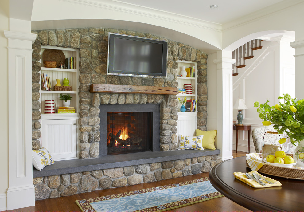 This is an example of a large traditional enclosed living room in Boston with white walls, medium hardwood floors, a standard fireplace, a stone fireplace surround, a wall-mounted tv and brown floor.