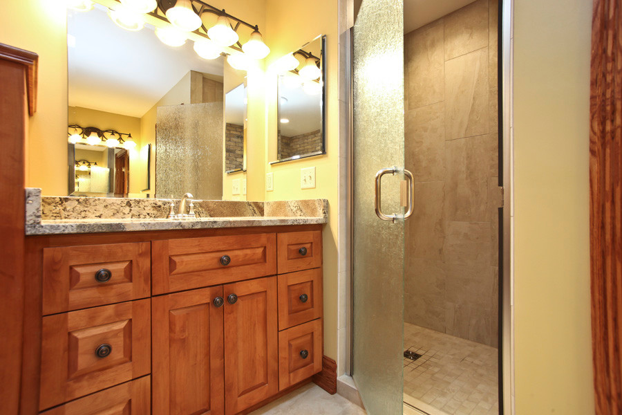 Large mountain style master beige tile and ceramic tile ceramic tile corner bathtub photo in Milwaukee with a console sink, shaker cabinets, medium tone wood cabinets, granite countertops, a two-piece toilet and yellow walls