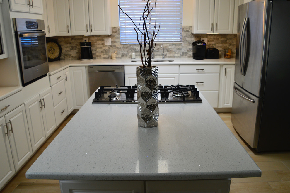 Example of a mid-sized transitional l-shaped porcelain tile enclosed kitchen design in Albuquerque with an undermount sink, raised-panel cabinets, white cabinets, quartz countertops, beige backsplash, porcelain backsplash, stainless steel appliances and no island