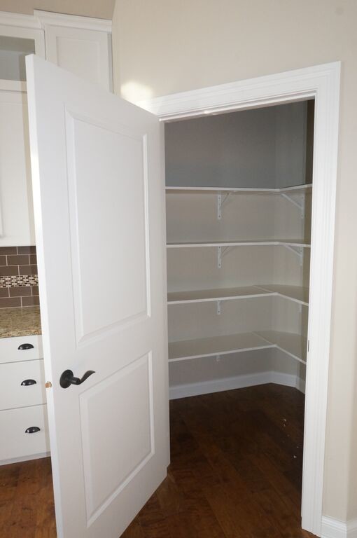 Design ideas for a small traditional gender-neutral walk-in wardrobe in Other with open cabinets, white cabinets and dark hardwood floors.