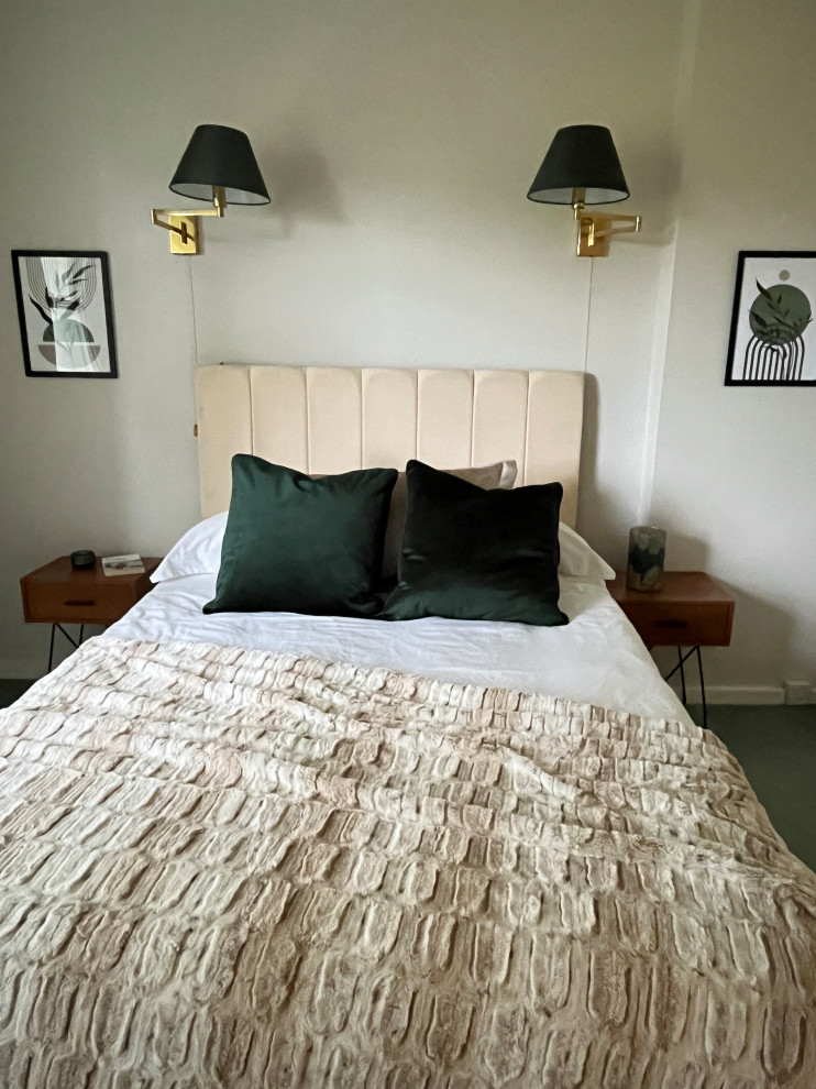 Medium sized contemporary master bedroom in London with beige walls, carpet and green floors.