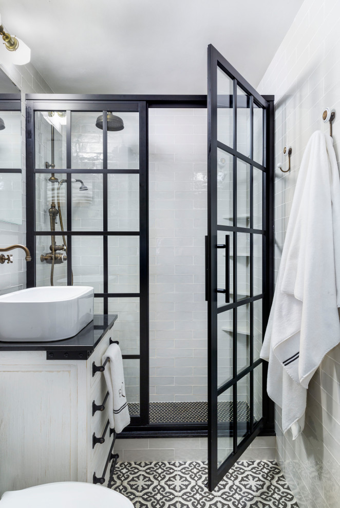 This is an example of a small transitional master bathroom in New York with furniture-like cabinets, white cabinets, an alcove shower, a two-piece toilet, blue tile, ceramic tile, white walls, cement tiles, a vessel sink, engineered quartz benchtops, black floor, a hinged shower door, white benchtops, a single vanity and a freestanding vanity.