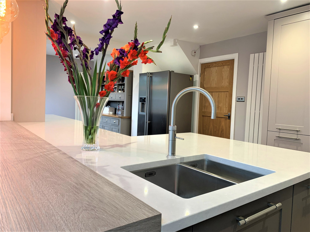 Photo of a medium sized traditional u-shaped kitchen/diner in Other with a double-bowl sink, shaker cabinets, quartz worktops, glass sheet splashback, stainless steel appliances, vinyl flooring and white worktops.