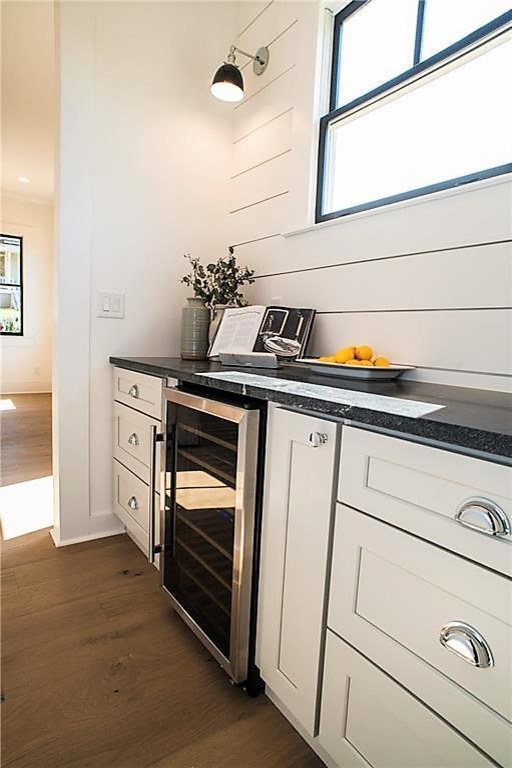 Inspiration for a mid-sized transitional l-shaped light wood floor and beige floor open concept kitchen remodel in Miami with an undermount sink, shaker cabinets, white cabinets, onyx countertops, white backsplash, wood backsplash, stainless steel appliances, an island and black countertops