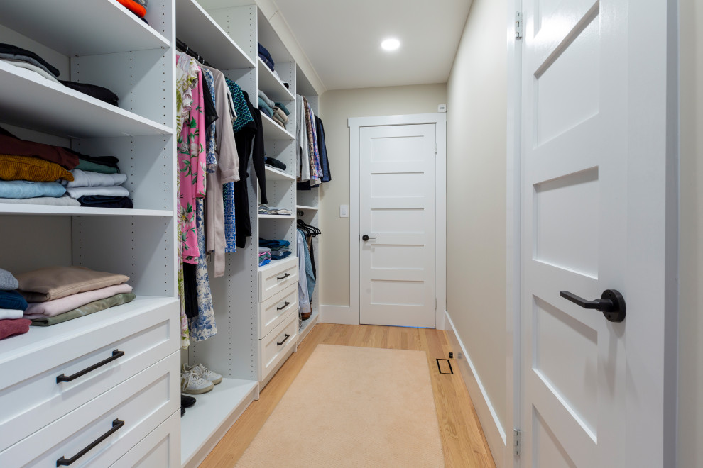 Imagen de armario vestidor unisex campestre de tamaño medio con armarios con paneles empotrados, puertas de armario blancas y suelo de madera en tonos medios