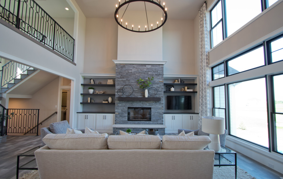 This is an example of a large formal open concept living room in Other with beige walls, vinyl floors, a standard fireplace, a corner tv, grey floor and vaulted.