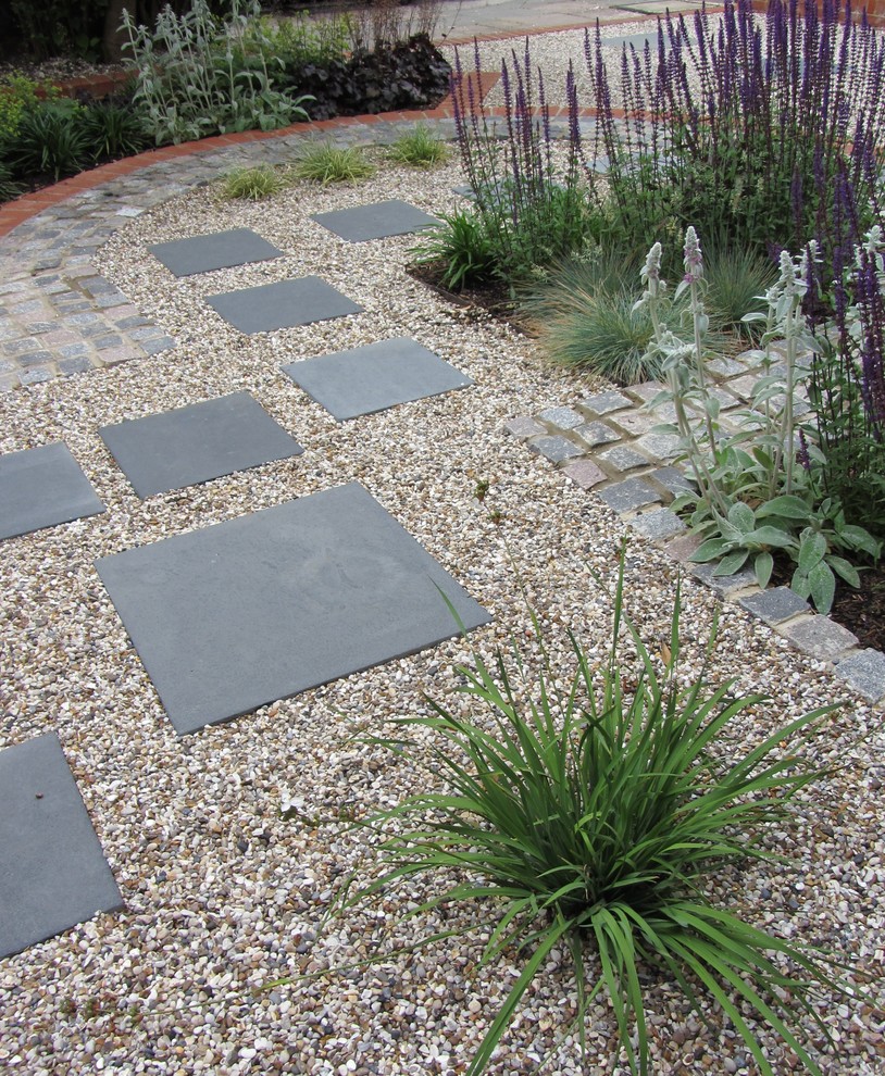 This is an example of a contemporary front yard driveway in Buckinghamshire with a garden path and concrete pavers.