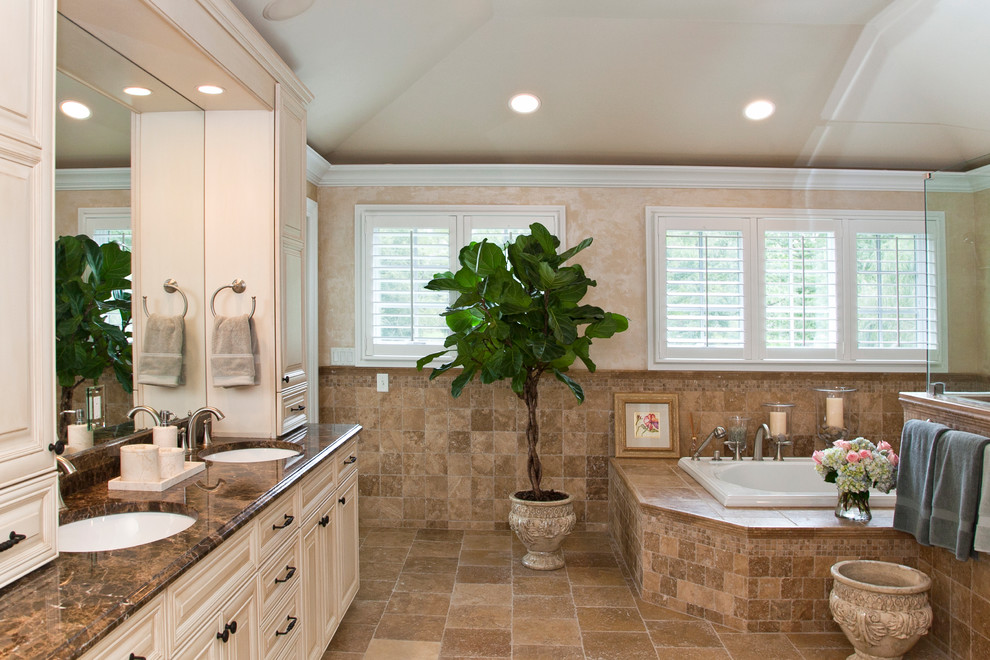 Inspiration for a large traditional master bathroom in Miami with raised-panel cabinets, light wood cabinets, a drop-in tub, brown tile, stone tile, beige walls, travertine floors, an undermount sink, granite benchtops, brown floor, an alcove shower and a hinged shower door.