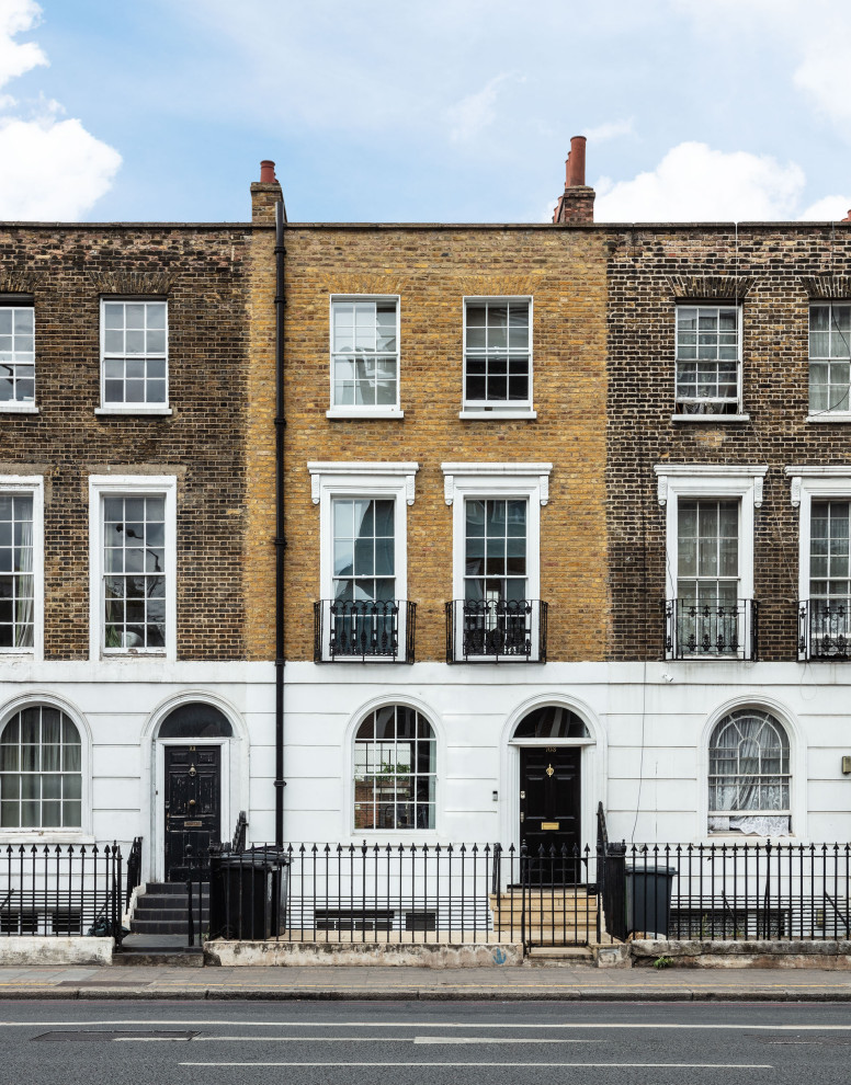 This is an example of a large traditional brick brown townhouse exterior in London with four or more storeys, a butterfly roof, a metal roof and a grey roof.
