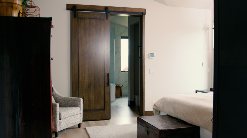 Imagen de dormitorio principal y abovedado campestre de tamaño medio sin chimenea con paredes blancas, suelo laminado y suelo beige