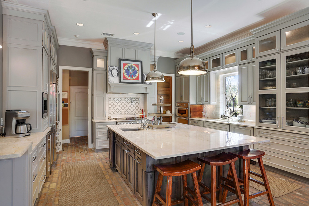 Inspiration for a transitional u-shaped kitchen in New Orleans with beaded inset cabinets, grey cabinets, with island, white splashback, stainless steel appliances and brick floors.