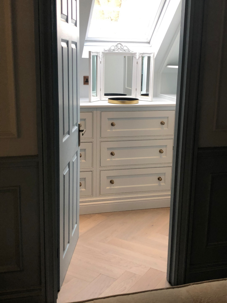 Photo of a small classic walk-in wardrobe for women in Sussex with recessed-panel cabinets, blue cabinets and medium hardwood flooring.