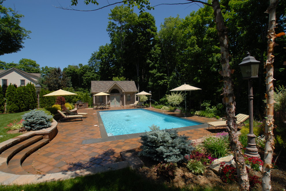 Pool house - backyard concrete paver and rectangular pool house idea in New York