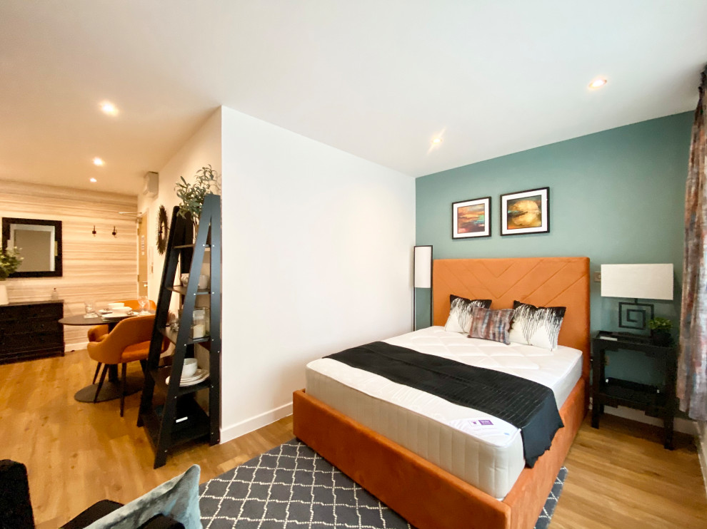 Kleines Modernes Hauptschlafzimmer mit blauer Wandfarbe, Laminat und orangem Boden in Sonstige