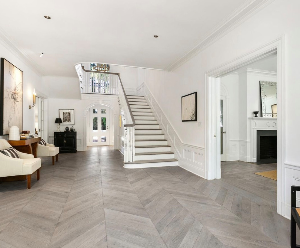 Photo of a large transitional foyer in Los Angeles with white walls, light hardwood floors, a single front door, a white front door, grey floor and decorative wall panelling.