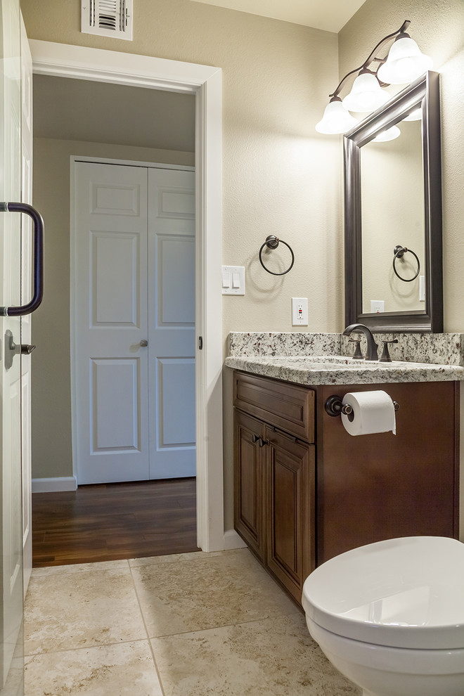 Example of a mid-sized transitional beige tile and porcelain tile porcelain tile and beige floor alcove shower design in Phoenix with shaker cabinets, dark wood cabinets, a two-piece toilet, beige walls, an undermount sink, granite countertops and a hinged shower door