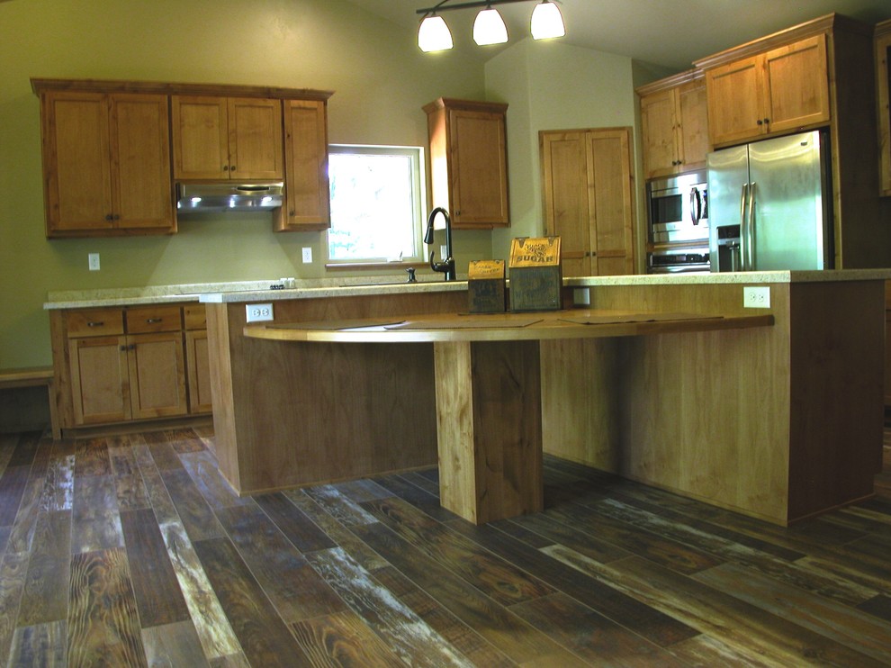 Example of a mountain style kitchen design with medium tone wood cabinets, granite countertops, stainless steel appliances and an island