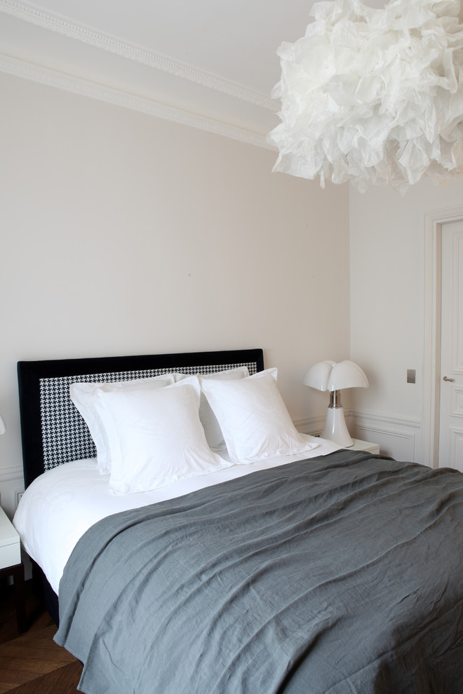Eclectic guest bedroom in Paris with white walls, dark hardwood floors and brown floor.